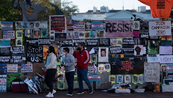 People walk past a temporary security fence around the White House covered in protest posters, as the 2020 US presidential election remains undecided on 4 November 2020, in Washington, DC.  - Sputnik International