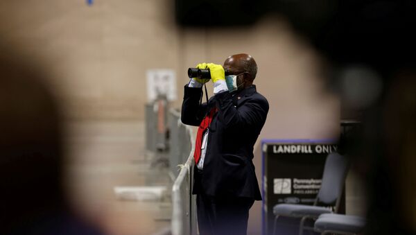 A poll watcher observes through a pair of binoculars as votes are counted at the Pennsylvania Convention Center on Election Day in Philadelphia, Pennsylvania, U.S. November 3, 2020. - Sputnik International