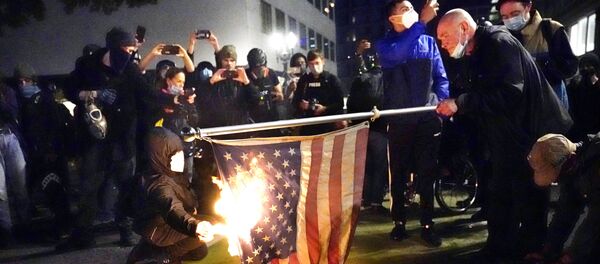 A protester lights an American flag on fire during a demonstration Wednesday, Nov. 4, 2020, in Portland, Ore - Sputnik International