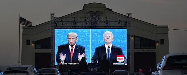 Elizabeth Allin, bottom center left, and Gideon Lett sit in a convertible while watching President Donald Trump, on left of video screen, and Democratic presidential candidate former Vice President Joe Biden speak during a Presidential Debate Watch Party at Fort Mason Center in San Francisco, Thursday, Oct. 22, 2020 - Sputnik International