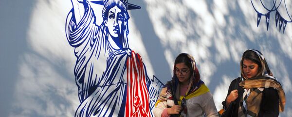 Women walk by mural on walls of former US Embassy compound in Tehran. File photo. - Sputnik International