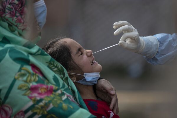 A Kashmiri girl reacts as a health worker takes a nasal swab sample to test for Covid-19 in Srinagar, Indian controlled Kashmir, Wednesday, 4 November 2020.  - Sputnik International