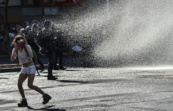 Demonstrators are sprayed by a riot police water cannon during a protest against Chilean President Sebastian Pinera's government in Santiago on 30 October 2020 - Sputnik International