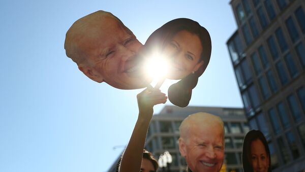 A supporter holds up cutouts of Joe Biden and Kamala Harris near the White House - Sputnik International