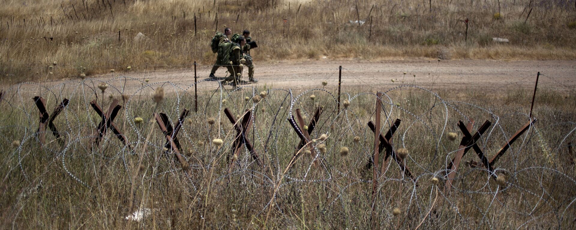 Israeli soldiers walk back from a position on the border with Syria on the Israeli controlled Golan Heights as smoke rises following explosions, Tuesday, July 16, 2013. - Sputnik International, 1920, 27.07.2024