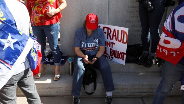 A supporter of U.S. President Donald Trump looks at her phone as others gather at a “Stop the Steal” protest after the 2020 U.S. presidential election was called for Democratic candidate Joe Biden, in front of the Arizona State Capitol in Phoenix, Arizona, U.S., November 7, 2020. - Sputnik International