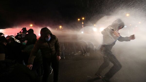 Demonstrators react as riot police use a water cannon during an opposition rally against the results of a parliamentary election, outside the Central Election Commission (CEC) building in Tbilisi, Georgia November 9, 2020. - Sputnik International