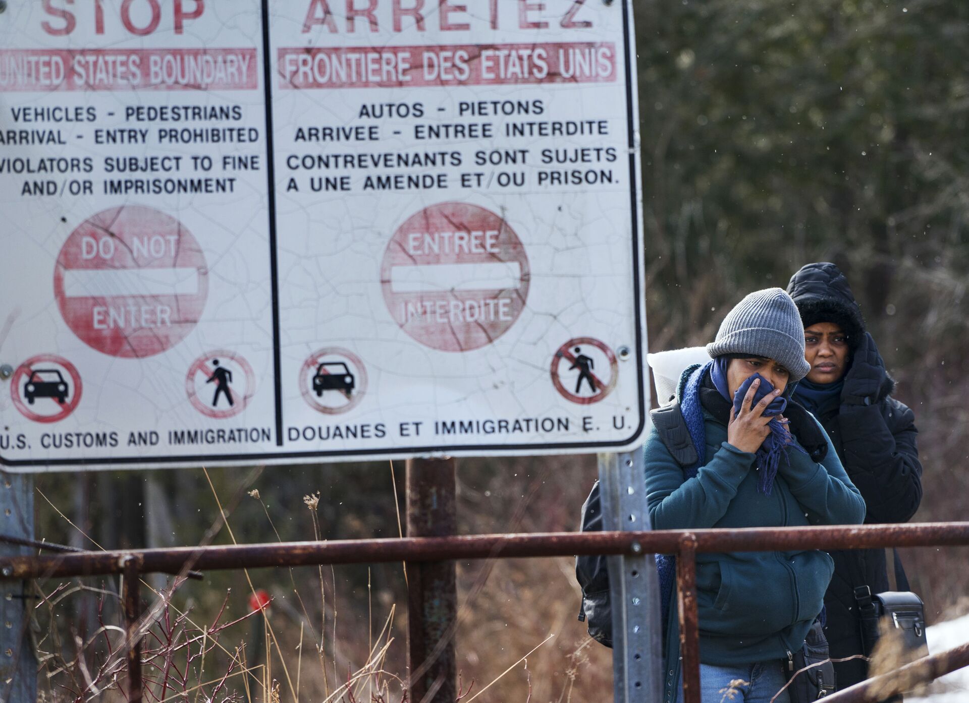 Two people, who later indicated to officials they are from Sudan, hesitate as they listen to a Royal Canadian Mounted Police officer tell them they will be taken into custody just before they crossed into Canada from Perry Mills, N.Y., near Hemmingford, Quebec, Sunday, Feb. 26, 2017 - Sputnik International, 1920, 07.09.2021