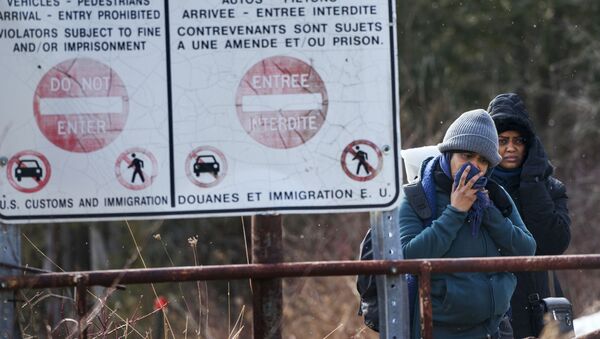 Two people, who later indicated to officials they are from Sudan, hesitate as they listen to a Royal Canadian Mounted Police officer tell them they will be taken into custody just before they crossed into Canada from Perry Mills, N.Y., near Hemmingford, Quebec, Sunday, Feb. 26, 2017 - Sputnik International