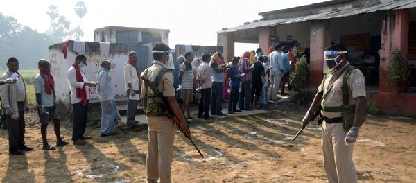 Policemen wearing protective face shields stand guard as voters stand in a queue to cast their vote outside a polling booth during the state assembly election, amidst the spread of the coronavirus disease (COVID-19), at a village on the outskirts of Patna, in the eastern state of Bihar, India, October 28, 2020 - Sputnik International