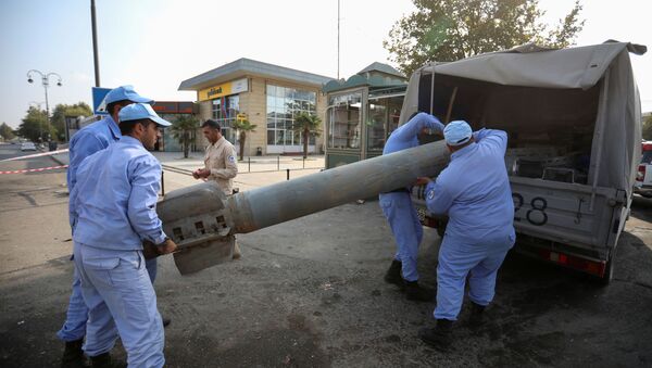 Azeri investigators load a fragment of an artillery shell in a street recently hit by shelling during a military conflict over the breakaway region of Nagorno-Karabakh, in the town of Barda, Azerbaijan October 29, 2020 - Sputnik International