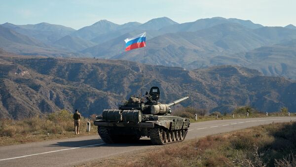 A service member of the Russian peacekeeping troops walks near a tank near the border with Armenia, following the signing of a deal to end the military conflict between Azerbaijan and ethnic Armenian forces, in the region of Nagorno-Karabakh, November 10, 2020. - Sputnik International