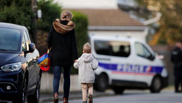 A woman holds her child by the hand on their way to the school in the area around the Bois d'Aulne college where Samuel Paty, the French teacher, was beheaded on the streets of the Paris suburb of Conflans-Sainte-Honorine, France, November 2, 2020 - Sputnik International