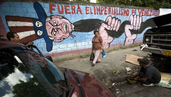 A man speaks to a pedestrian next to a graffiti that reads Imperialism get out of Venezuela at Catia shanty town, in Caracas, Thursday, Nov. 15, 2007 - Sputnik International