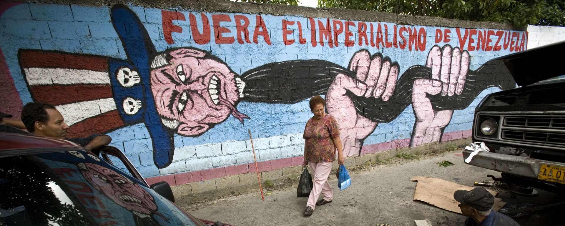 A man speaks to a pedestrian next to a graffiti that reads Imperialism get out of Venezuela at Catia shanty town, in Caracas, Thursday, Nov. 15, 2007 - Sputnik International, 1920, 16.07.2024