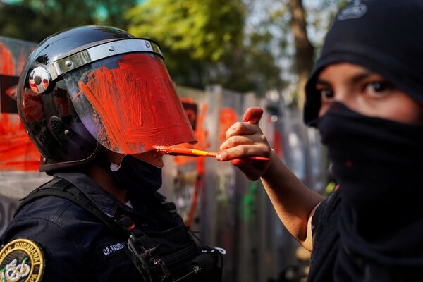 A member of a feminist collective paints the helmet of a riot police officer during a protest against gender and police violence, in Mexico City, Mexico 11 November 2020.  - Sputnik International