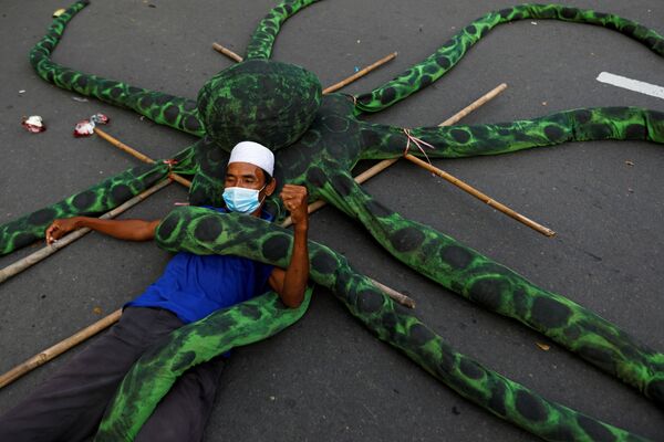 A fisherman wearing a protective mask lies on an artificial octopus during a protest against the government's labour reforms in a job creation Bill in Jakarta, Indonesia, 10 November 2020.  - Sputnik International