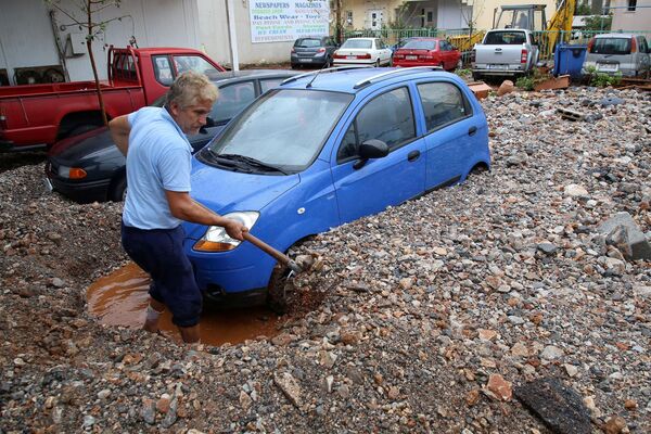 A local shovels mud blocking a car, after heavy rainfall in Malia on the island of Crete, Greece, 10 November 2020. - Sputnik International