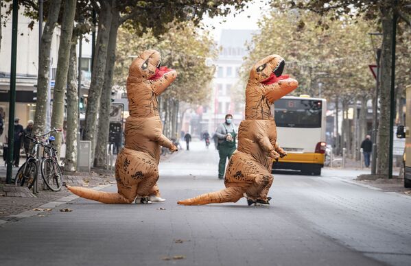 Two carnival-goers in inflatable dinosaur costumes cross a street near the Schillerplatz in Mainz, Germany, 11 November 2020.  - Sputnik International