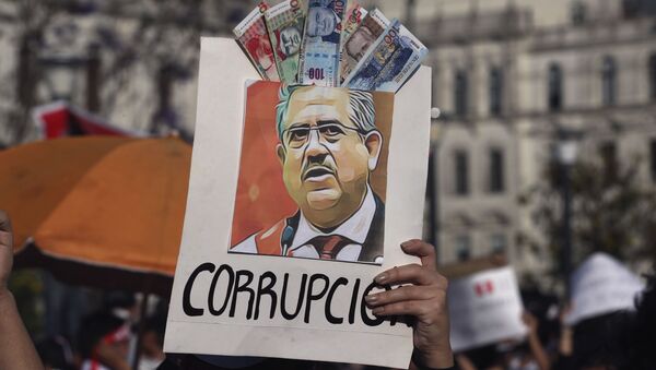 A protester holds up a poster adorned with play money with the Spanish word for corruption and an image depicting Peru's newly sworn-in president Manuel Merino - Sputnik International