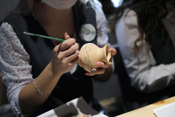 A woman paints on a jug during a master class at the Slobozhanschina historical and cultural complex in the Belgorod Region.  - Sputnik International