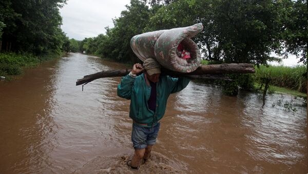 A man carries his belongings through a flooded road after the passing of Storm Iota, in Marcovia, Honduras November 18, 2020. - Sputnik International