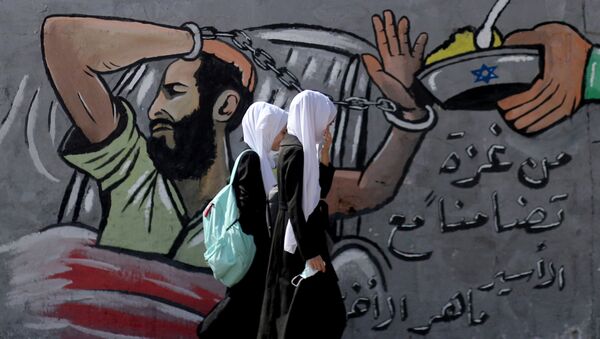 FILE PHOTO: Palestinian students walk past a mural depicting hunger-striking Palestinian prisoner Maher Al-Akhras, who is held by Israel, in the central Gaza Strip October 19, 2020 - Sputnik International