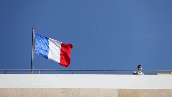 A man stands near a French flag as it flutters atop the roof of the French Embassy as protesters, including members of the Islamic Movement in Israel, demonstrate against the publications of a cartoon of Prophet Mohammad in France and French President Emmanuel Macron's comments, near the French Embassy in Tel Aviv, Israel October 29, 2020. - Sputnik International