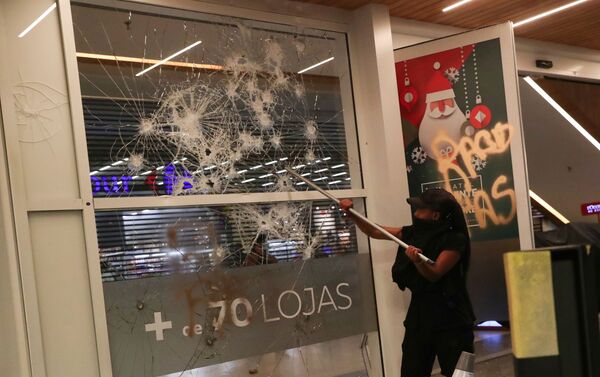 A demonstrator damages glass at a shopping mall during a march in Sao Paulo on National Black Consciousness Day and in protest against the death of Joao Alberto Silveira Freitas, a Black man beaten to death at a market in Porto Alegre, Brazil, November 20, 2020.  - Sputnik International