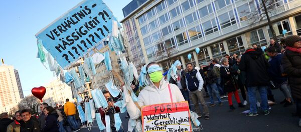 A demonstrator holds a sign with face masks hanging from it during a rally against the government's restrictions following the coronavirus disease (COVID-19) outbreak, in Leipzig, Germany, November 7, 2020.  - Sputnik International