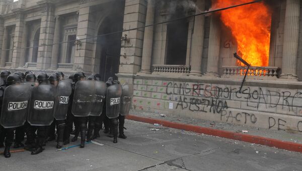Riot police stand in formation as demonstrators set an office of the Congress building on fire during a protest demanding the resignation of President Alejandro Giammattei, in Guatemala City, Guatemala November 21, 2020. - Sputnik International