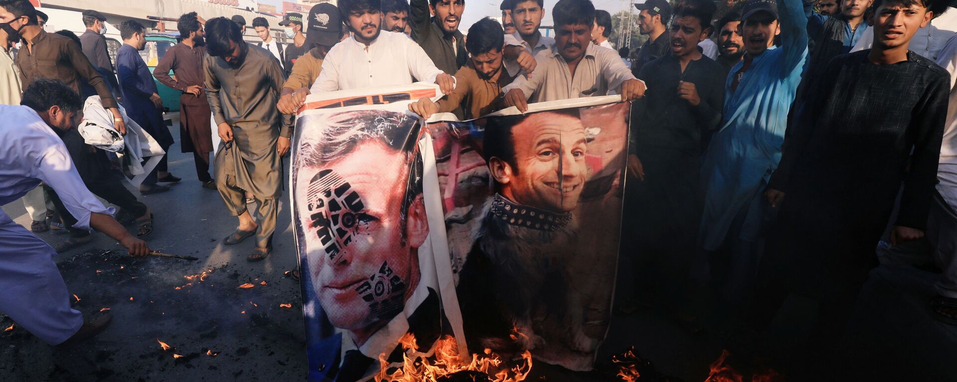 People chant slogans as they set fire to a banner with an image of French President Emmanuel Macron during a protest against cartoon publications of Prophet Mohammad in France and French President Emmanuel Macron's comments, in Peshawar, Pakistan 27 October 2020. - Sputnik International, 1920, 22.11.2020