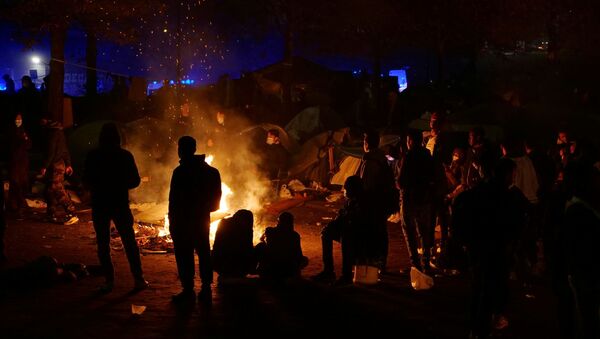 Migrants are seen in silhouette as they gather near a fire before being evacuated by French gendarmes at a makeshift migrant camp near the A1 highway in Saint-Denis near Paris, France, November 17, 2020. - Sputnik International