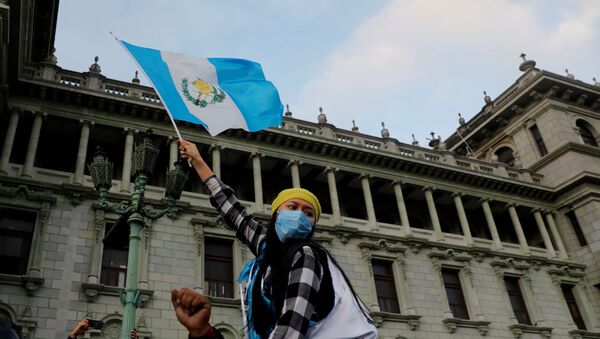 A woman holds up a Guatemalan flag, during a protest to demand the resignation of President Alejandro Giammattei, a day after demonstrators set fire to a part of the Congress building in Guatemala City, Guatemala November 22, 2020. - Sputnik International