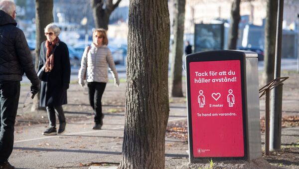People strollIing in the cold but sunny weather pass a sign asking to maintain social distancing, amid the continuous spread of the coronavirus disease (COVID-19) pandemic, in Stockholm, Sweden, November 20, 2020 - Sputnik International
