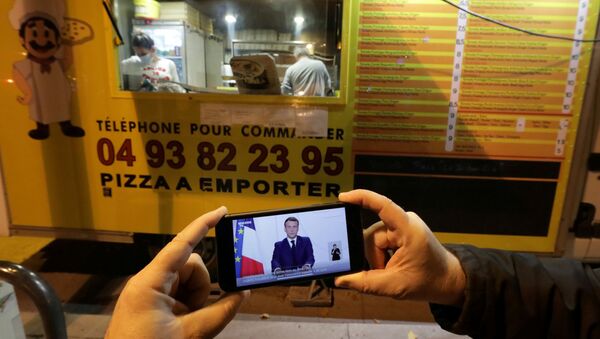 FILE PHOTO: A man watches French President Emmanuel Macron on his mobile phone as he stands near a pizza van as he addresses the nation about the coronavirus disease (COVID-19) outbreak and the lockdown restrictions, in Nice, France November 24, 2020 - Sputnik International