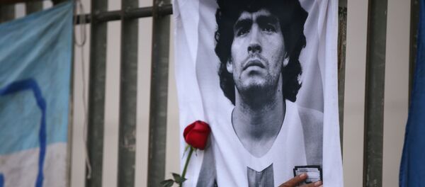 A rose is placed next to a banner of Argentine soccer great Diego Maradona as fans gather to mourn his death, at the Obelisk of Buenos Aires, Argentina November 25, 2020 - Sputnik International