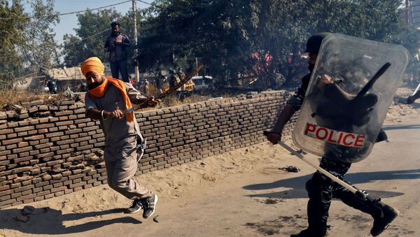 A policeman chases away a farmer during a protest against the newly passed farm bills at Singhu border near Delhi, India - Sputnik International