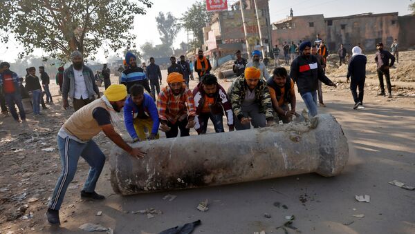 Farmers push a cement pipe to use it as a roadblock during a protest against the newly passed farm bills at Singhu border near Delhi - Sputnik International