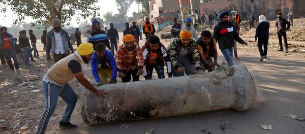 Farmers push a cement pipe to use it as a roadblock during a protest against the newly passed farm bills at Singhu border near Delhi - Sputnik International
