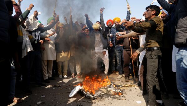 Farmers shout slogans as they burn an effigy during a protest against the newly passed farm bills at Singhu border near Delhi - Sputnik International