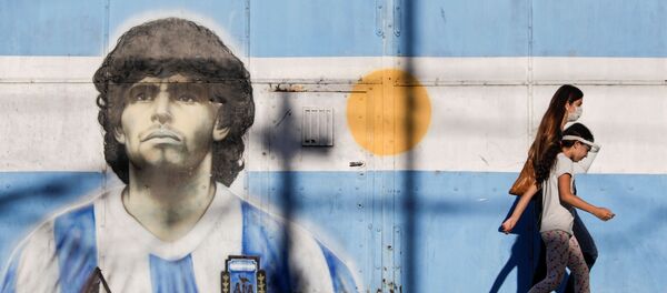 People walk past graffiti of soccer legend Diego Armando Maradona in Buenos Aires, Argentina, 27 November 2020. - Sputnik International