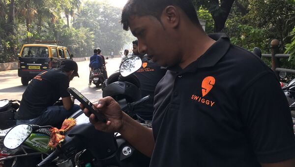 In this photograph taken on December 24, 2018, an Indian delivery man working with the food delivery app Swiggy checks his phone in a business district in Mumbai - Sputnik International