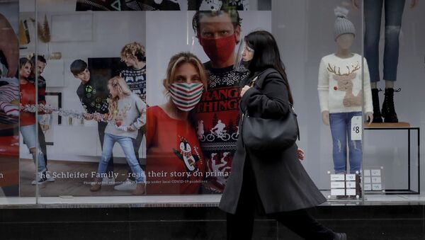 A woman wearing a face shield walks past the front window of the Primark clothing store on Oxford Street during England's second coronavirus lockdown, in London, Monday, Nov. 23, 2020 - Sputnik International