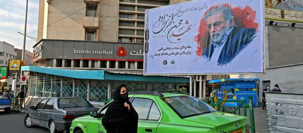 A woman walk by a billboard in honour of slain nuclear scientist Mohsen Fakhrizadeh in the Iranian capital Tehran, on November 30, 2020 - Sputnik International