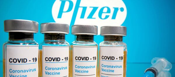 Vials with a sticker reading, COVID-19 / Coronavirus vaccine / Injection only and a medical syringe are seen in front of a displayed Pfizer logo in this illustration taken October 31, 2020 - Sputnik International