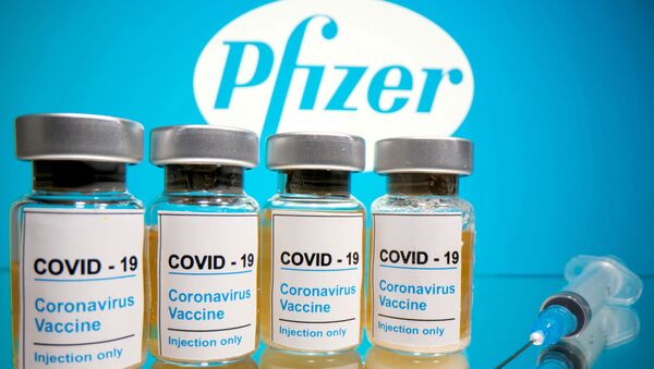 Vials with a sticker reading, COVID-19 / Coronavirus vaccine / Injection only and a medical syringe are seen in front of a displayed Pfizer logo in this illustration, taken 31 October 2020 - Sputnik International