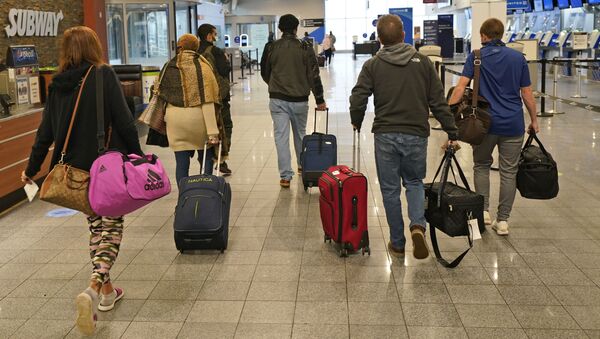 Travelers walk through the terminal at Cleveland Hopkins International Airport before boarding a plane, Wednesday, Nov. 25, 2020, in Cleveland. - Sputnik International