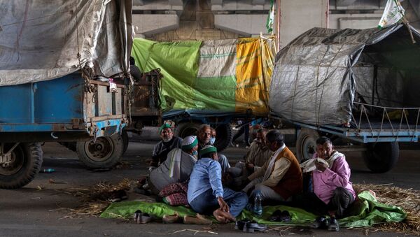 Farmers rest near their parked tractor trolleys at the site of a protest against the newly passed farm bills at the Delhi-Uttar Pradesh border in Ghaziabad, India - Sputnik International
