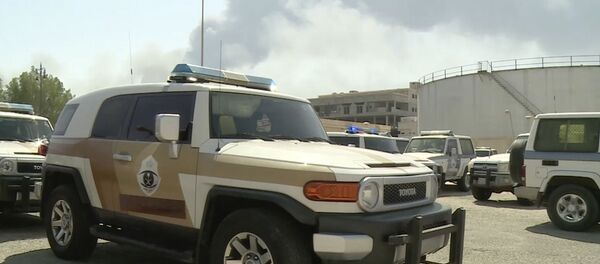 In this image made from a video broadcast on the Saudi-owned Al-Arabiya satellite news channel on Saturday, Sept. 14, 2019, a Saudi police cruiser sits in a parking lot as the smoke from a fire at the Abqaiq oil processing facility can be seen behind it in Buqyaq, Saudi Arabia In this image made from a video broadcast on the Saudi-owned Al-Arabiya satellite news channel on Saturday, Sept. 14, 2019, a Saudi police cruiser sits in a parking lot as the smoke from a fire at the Abqaiq oil processing facility can be seen behind it in Buqyaq, Saudi Arabia - Sputnik International